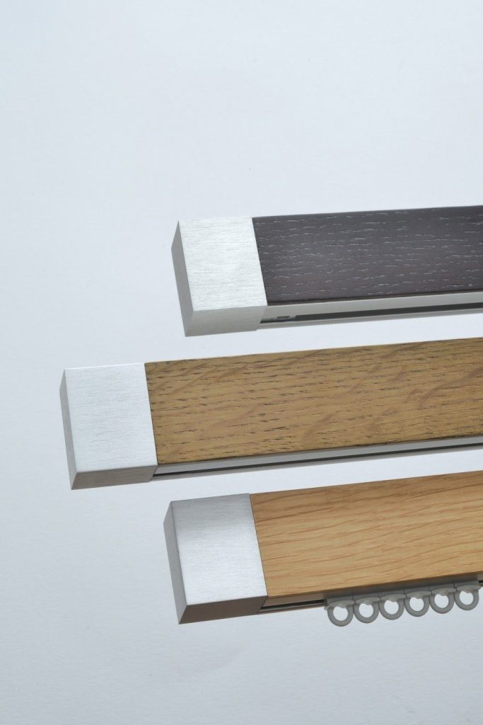 Trois rails à rideaux habillés de bois clair, de bois foncé et de métal