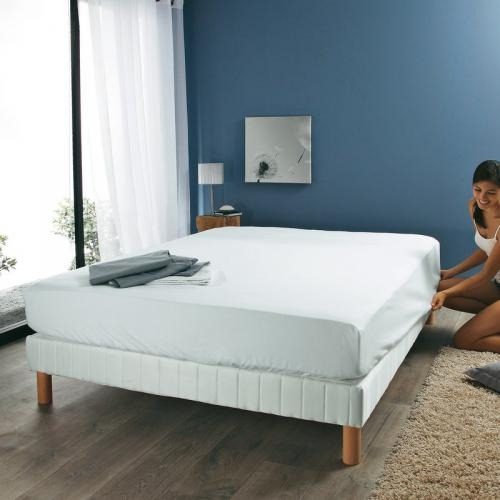 Lit équipé d'une protection de matelas blanche dans une chambre aux murs bleus