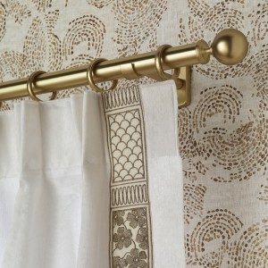 Rideau blanc à galon brodé devant un papier peint à motifs de cercles ocre sur fond clair