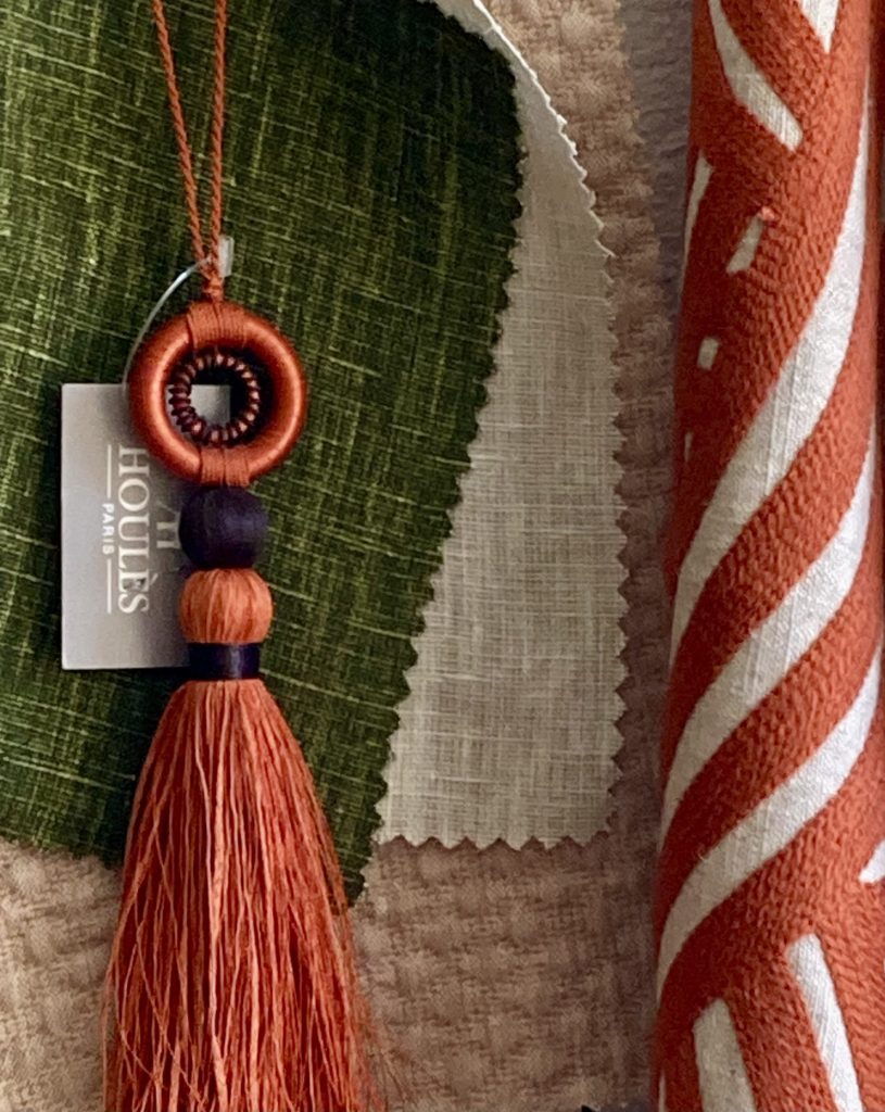 Gland de passementerie terracotta posé sur des tissus d'éditeur