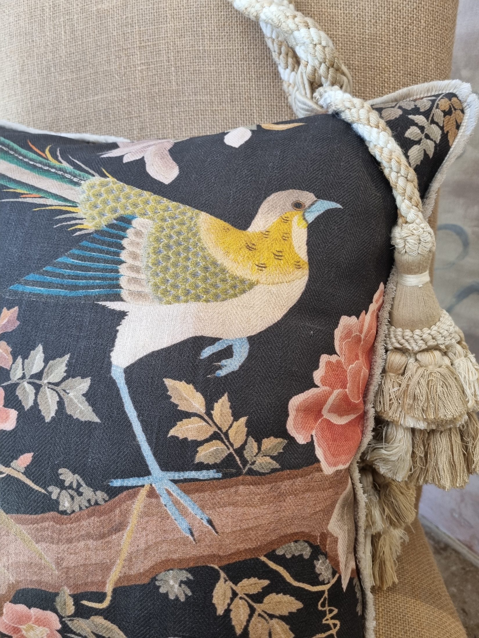 Coussin imprimé d'un oiseau sur fond sombre, orné d'un gland de passementerie